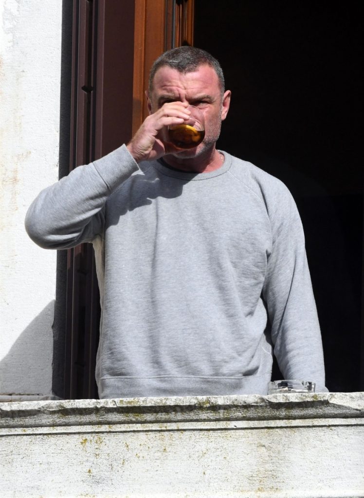 Liev toma una copa asomado al balcón de su residencia