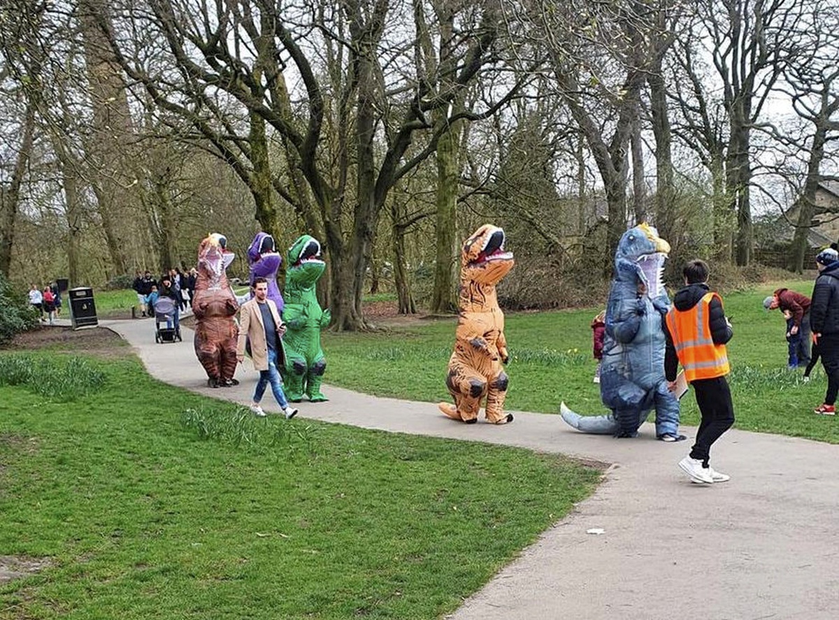 Varias personas disfrazadas de dinosaurio en un parque