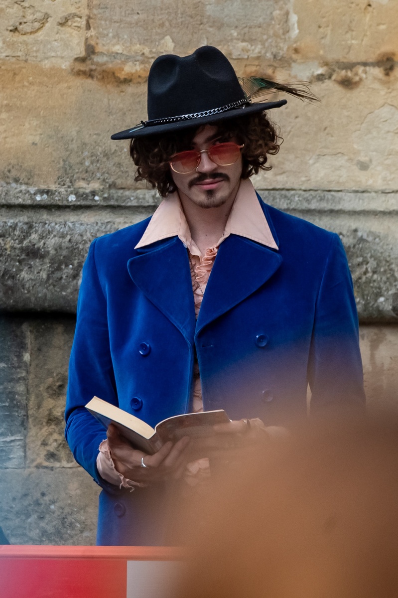 Un actor con sombrero y gafas de sol leyendo un libro se dispone a rodar su escena en Wonka