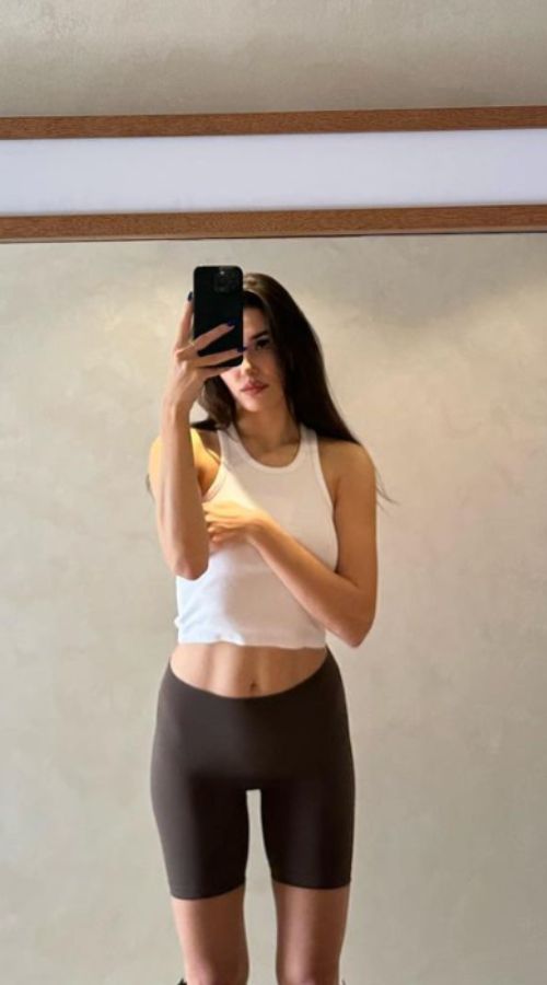 Foto de Hande Erçel en ropa deportiva, mostrando ombligo y en mallas cortas